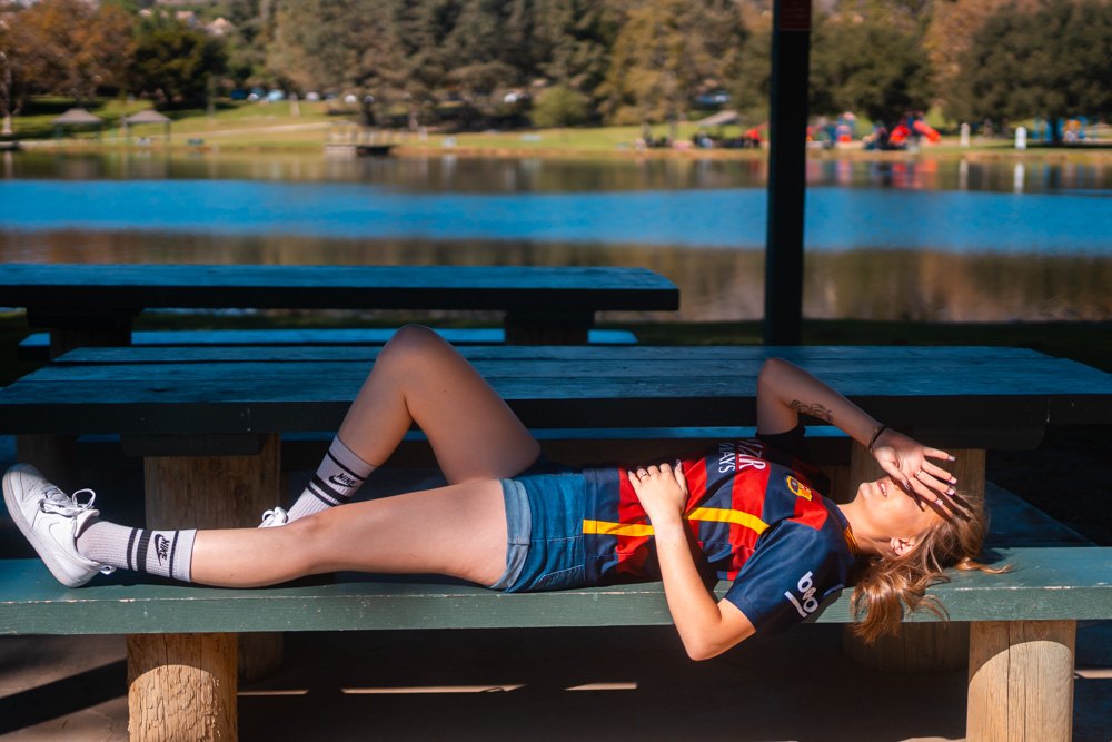 Lying on a picnic table shading her eyes