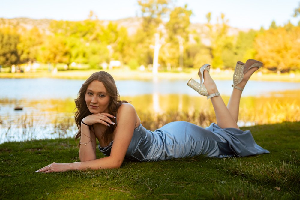 Lying on the grass, heels raised, lake behind
